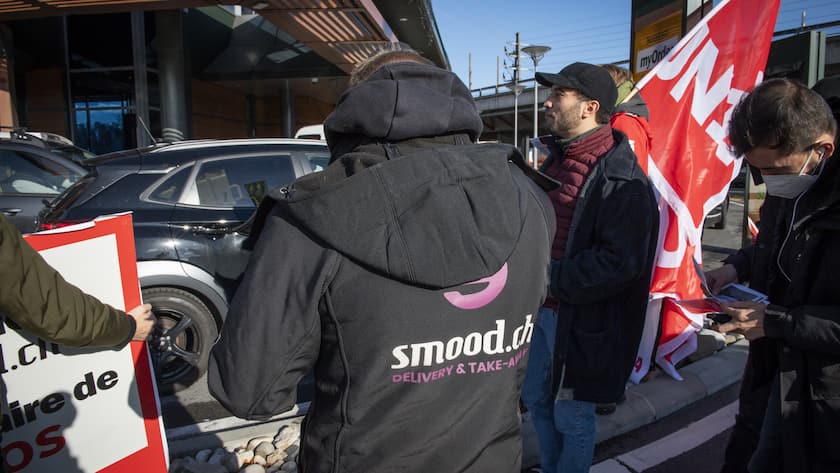 Un groupe de livreurs grevistes de l'entreprise Smood et des militants d Unia manifestent devant le siege de Mc Donald a midi ce vendredi 3 decembre 2021 a Crissier. Ils ont brievement gene la fluidite du Mc drive et distribue des tracts pour une amelioration de leurs conditions de travail.(KEYSTONE/Jean-Guy Python)