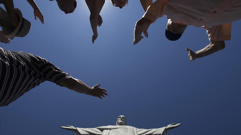 Visitors raise their arms to pray below the Christ Redeemer statue in Rio de Janeiro, Brazil, Tuesday, Jan. 21, 2014. Rio de Janeiro's famed Christ statue is being repaired after two fingers and its head were chipped during recent lightning storms. (AP Photo/Felipe Dana)
