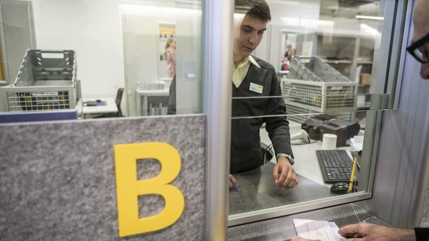 Kunde zahlt Gel mit einem roten Einzahlungsschein an einem Postschalter ein.