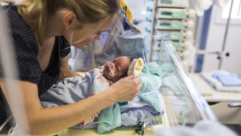 Eine Mutter bürstet einem Neugeborenen die Haare im Spital.