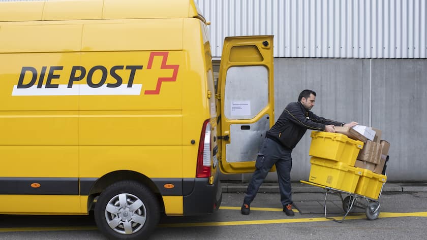 Pöstler ladet Pakete auf einen Handwagen aus einem gelben Post-Auto.