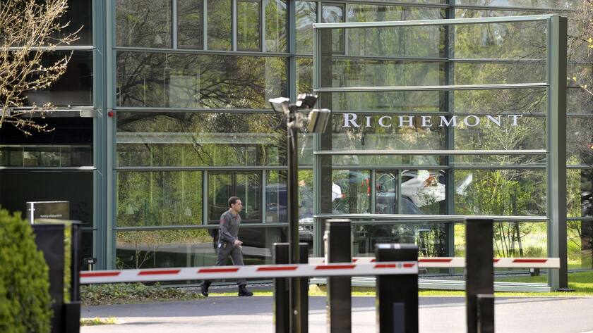 Logo von Richemont auf einem Glasgebäude. Eine Person läuft daran vorbei