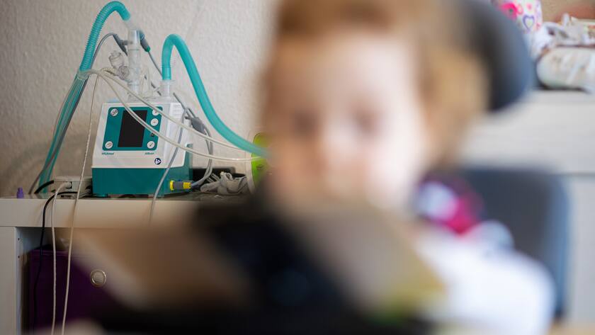 Verschwommen ist ein Kleinkind zu sehen, im Hintergrund steht eine Medizinische Maschine.