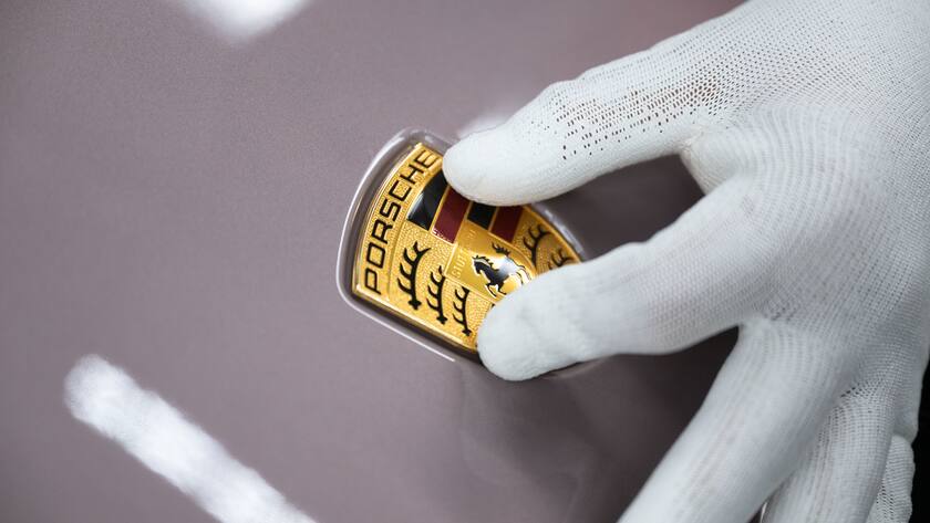 PRODUKTION - 26.09.2022, Baden-Württemberg, Stuttgart: Ein Mitarbeiter der Porsche AG zeigt in einer Produktionshalle des Porsche-Stammwerks das Porsche-Logo. Der Volkswagen-Konzern wird seine Sportwagentochter Porsche AG an die Börse bringen. Foto: Marijan Murat/dpa +++ dpa-Bildfunk +++