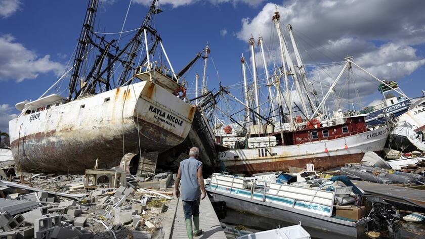 Snowbird Bruce Hickey, 70, walks along the waterfront, now littered with debris including shrimp boats, in the mobile home park where he and his wife Kathy have a winter home, a trailer originally purchased by Kathy's mother in 1979, on San Carlos Island, Fort Myers Beach, Fla., Wednesday, Oct. 5, 2022, one week after the passage of Hurricane Ian. (AP Photo/Rebecca Blackwell)