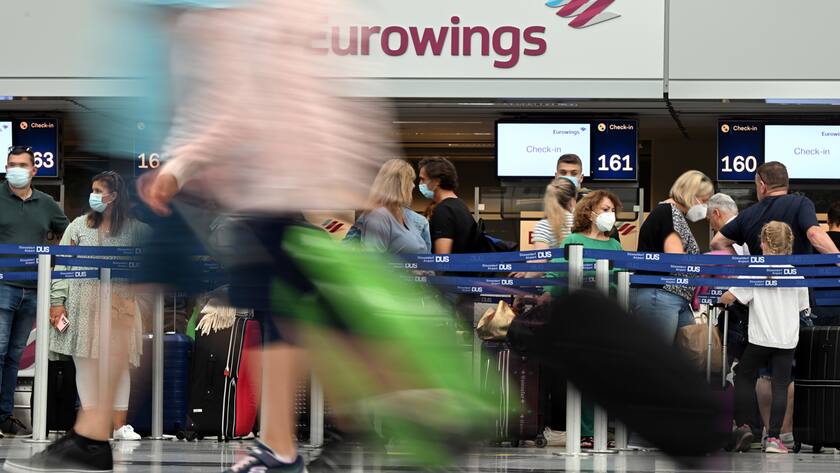 Passagiere vor Eurowings Schild am Check-in.