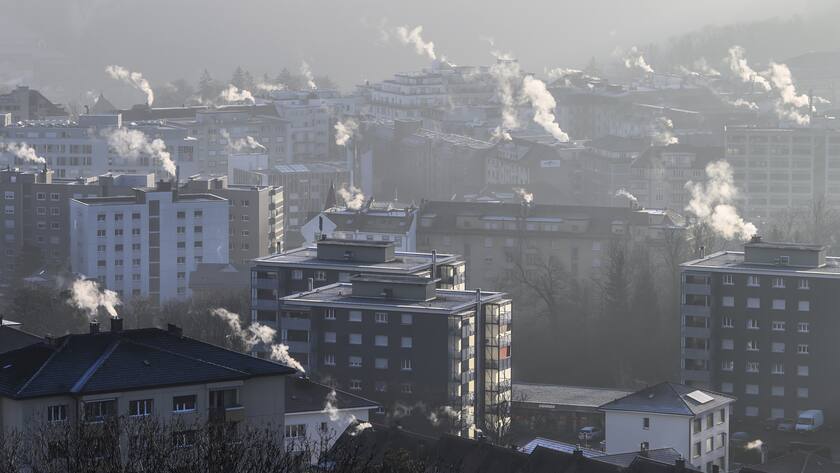 De la fumee s'echappe des cheminees sur les toits des immeubles, ce vendredi 14 janvier 2022 a Fribourg. (KEYSTONE/Anthony Anex)