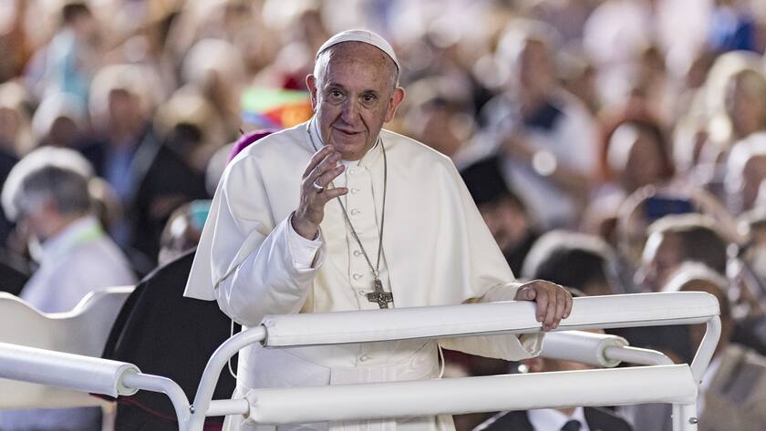 Papst Franziskus in einer Menschenmenge in Genf. Er hält die linke Hand etwas in die Höhe.