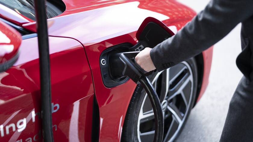 Ein Mann schliesst ein Audi e-tron-Auto an eine der vier Ladestationen des Audi charging hub in Zuerich an.