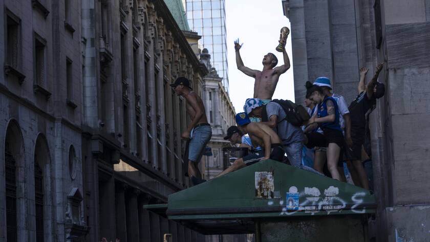 Soccer fans continue to celebrate outside the Casa Rosada presidential palace, despite waiting for hours for a homecoming parade for the players who won the World Cup title that was abruptly cut short, in Buenos Aires, Argentina, Tuesday, Dec. 20, 2022. A parade to celebrate the Argentine World Cup champions was abruptly cut short Tuesday as millions of people poured onto thoroughfares, highways and overpasses in a chaotic attempt to catch a glimpse of the national team. (AP Photo/Rodrigo Abd)