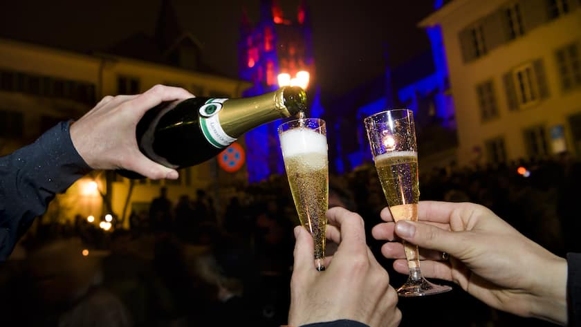 Des personnes boivent du champagne dans des coupes lors du passage de la nouvelle annee 2018 devant l'illumination de la Cathedrale de Lausanne durant la nuit du dimanche 31 decembre 2017 au lundi 1 janvier 2018 a Lausanne. (KEYSTONE/Jean-Christophe Bott)