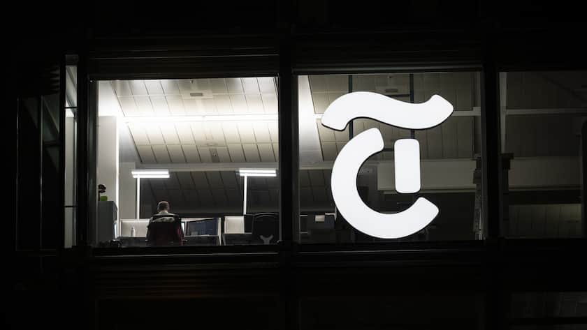 Ein Mann arbeitet an einem Schreibtisch im Buero neben dem Logo der Mediengruppe Tamedia, neu TX Group AG, aufgenommen am Mittwoch, 11. Januar 2023 in Zuerich. (KEYSTONE/Ennio Leanza)