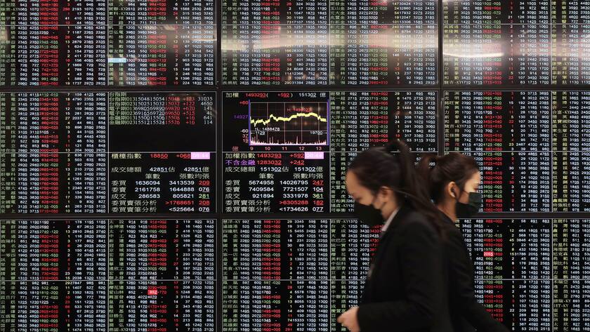 People walk past an electronic stock board at Taipei Exchange in Taipei, Taiwan, Monday, Jan. 30, 2023.
