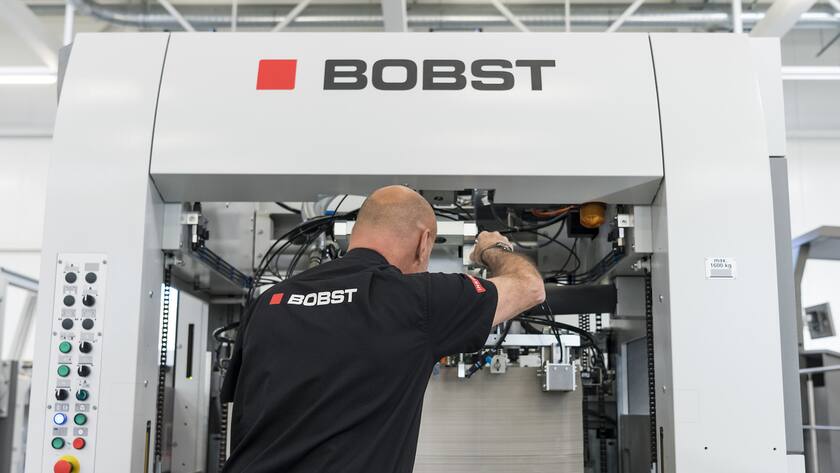 Ein Mitarbeiter des Unternehmens Bobst inspiziert eine Kartonschneidemaschine im Kompetenzzentrum der Bobst-Gruppe.