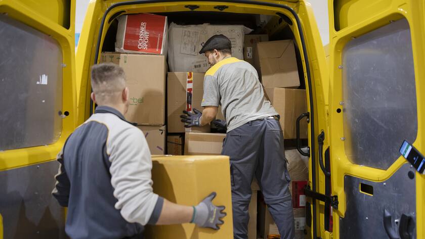 Paketboten der Schweizerischen Post beladen einen Lieferwagen fuer die Zustellung, in der Distributionsbasis Frauenfeld, am Dienstag, 13. Dezember 2022 in Frauenfeld. Zwischen Black Friday und Weihnachten verarbeiten die Mitarbeitenden der Post durchschnittlich gegen 1 Million Pakete pro Tag, an Spitzentagen bis zu 1,3 Millionen Pakete. (KEYSTONE/Michael Buholzer)