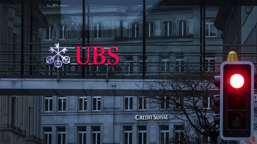 The logos of the Swiss banks Credit Suisse and UBS are displayed on different buildings behind traffic lights in Zurich, Switzerland on Sunday March 19, 2023. (KEYSTONE/Michael Buholzer).