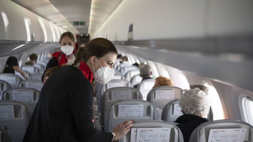 Cabin Crew-Mitglieder der Schweizer Fluggesellschaft Helvetic Airways bedienen mit den vorgeschriebenen Atemschutzmasken Fluggaeste auf einem Flug von Wien nach Zuerich in der Kabine einer Helvetic Embraer E190-E2, fotografiert am 13. Maerz 2021. (KEYSTONE/Christian Beutler)
