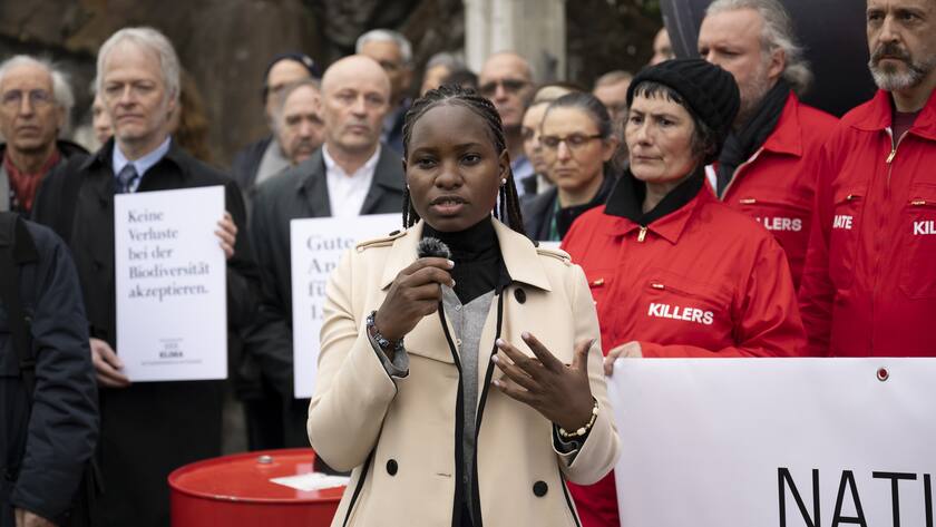 Ugandan climate and environmental rights activist from the Fridays for Future (FFF) movement, Hilda Flavia Nakabuye speaks front of Climate activists holding a banner reading in German: "the National Bank finances the climat crisis" during a protest prior to the 115. Ordinary General Assembly of Swiss National Bank (SNB), at Bern, Switzerland, this Friday, April 28, 2023. (KEYSTONE/Anthony Anex)