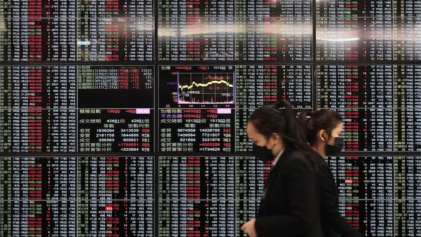 People walk past an electronic stock board at Taipei Exchange in Taipei, Taiwan, Monday, Jan. 30, 2023. Shares were trading mixed in Asia on Monday after Wall Street benchmarks closed higher on Friday, capping a third week of gains out of the last four. (AP Photo/Chiang Ying-ying)