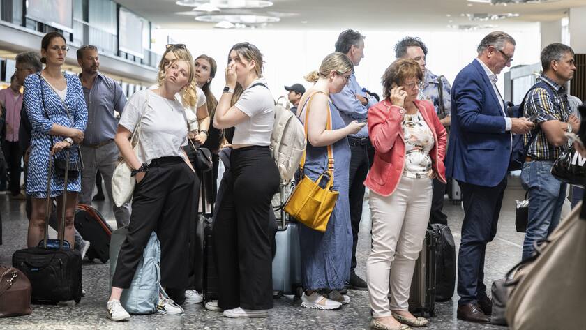 Fluggaeste warten vor einer Anzeigetafel am Mittwoch, 15. Juni 2022, auf dem Flughafen in Zuerich. Wegen einer Informatikpanne von Skyguide sind die Flughaefen Zuerich und Genf derzeit lahmgelegt. Es koennen weder Flugzeuge starten noch landen, wie eine Sprecherin in Zuerich auf Anfrage sagte. Auch Ueberfluege ueber die Schweiz sind nicht moeglich. (KEYSTONE/Ennio Leanza).