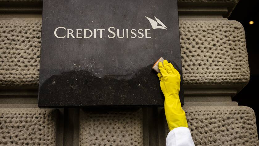 An activist of Scientist Rebellion cleans symbolically.the entrance of the Swiss Bank Credit Suisse at Paradeplatz during a protest against fossil fuel investments, in Zurich, Switzerland on Wednesday May 10, 2023. (KEYSTONE/Michael Buholzer)