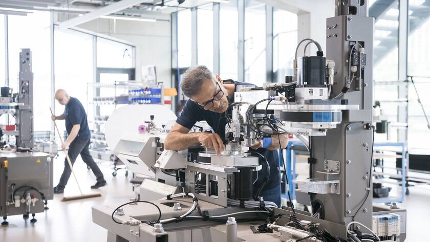 Ein Montagearbeiter arbeitet an der Endmontage einer Maschine Alpha 530 am Hautpsitz der Firma Komax, aufgenommen am 2. Juni 2022, in Dierikon, Kanton Luzern. Die Firma Komax ist ein global taetiges Technologieunternehmen im Bereich automatisierte Kabelverarbeitung, die die Herstellung von Maschinen fuer die Produktion von Kabelbaeumen, also fuer die Buendelung von Kabeln, spezialisiert ist. Sie erwirtschaftet 80% ihres Umsatzes mit Kunden aus der Automobilbranche. (KEYSTONE/Goran Basic)