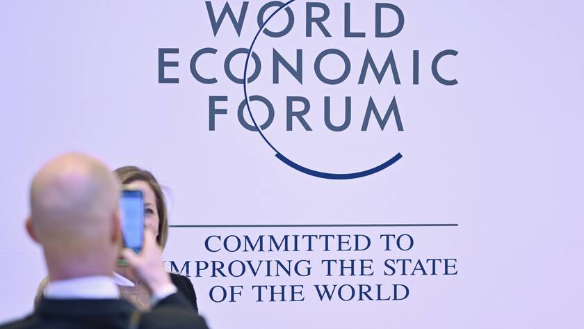A man takes a picture of a woman in front of the WEF logo on the closing day of the 53rd annual meeting of the World Economic Forum, WEF, in Davos, Switzerland, Friday, January 20, 2023. The meeting brings together entrepreneurs, scientists, corporate and political leaders in Davos under the topic "Cooperation in a Fragmented World" from 16 to 20 January. (KEYSTONE/Gian Ehrenzeller)