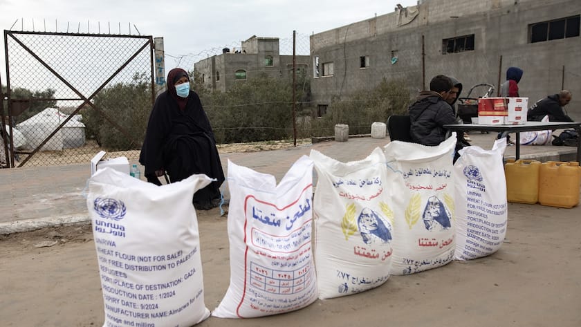 epa11110540 A Palestinian woman stands next to flour bags distributed by UNRWA (United Nations Relief and Works Agency for Palestine Refugees in the Near East) in Rafah, southern Gaza Strip, 28 January 2024. Several Western countries have suspended or reviewed funding to the UN agency for Palestinians following Israel?s allegations that some UNRWA staff members had been involved in the 07 October 2023 Hamas attacks. EPA/HAITHAM IMAD