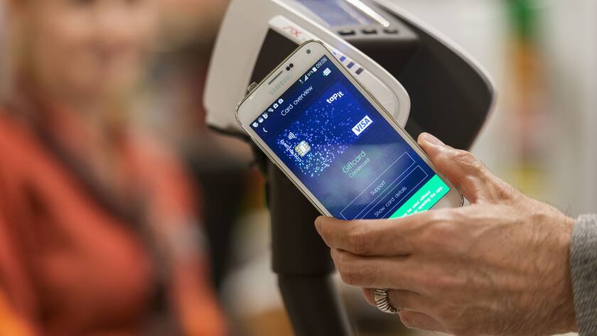 Bezahlen mit der "Tapit" App auf dem Smartphone an der Kasse einer Migros Filiale in Zuerich am Dienstag, 8. Juli 2014. Mit "Tapit" kommt erstmals eine Smartphone App auf den Schweizer Markt, die das Bezahlen, Sammeln von Treuepunkten und Oeffnen von Tueren in einem einzigen, neutralen Oekosystem erlaubt. Tapit ermoeglicht zunaechst das bargeldlose Bezahlen in Laeden in der Schweiz und im Ausland. (KEYSTONE/Christian Beutler)