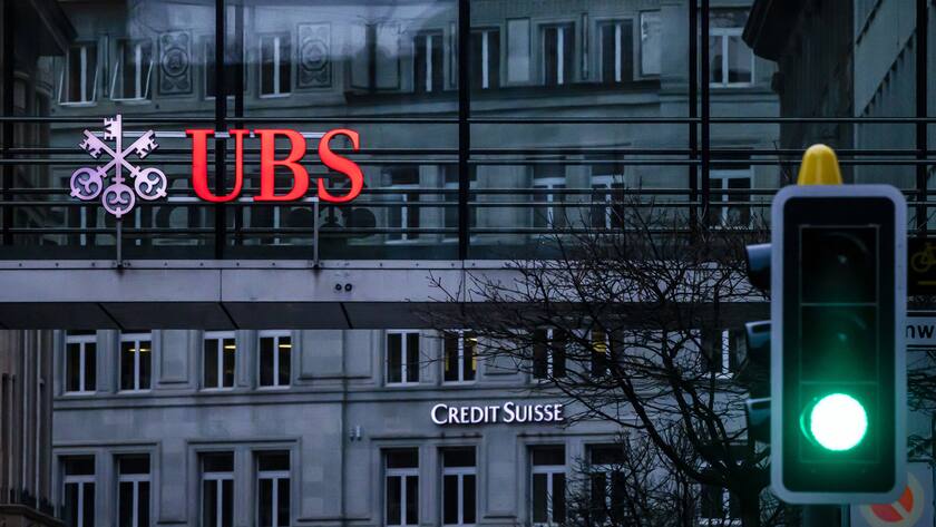 The logos of the Swiss banks Credit Suisse and UBS are displayed on different buildings behind traffic lights in Zurich, Switzerland on Sunday March 19, 2023. (KEYSTONE/Michael Buholzer).