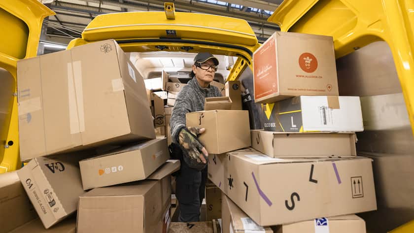 Der Paketbote der Schweizerischen Post Carlos Hugo Vega sortiert Pakete beim Beladen der Lieferwagen fuer die Zustellung, in der Distributionsbasis Oerlikon, aufgenommen am Dienstag, 5. Dezember 2023 in Zuerich. (KEYSTONE/Michael Buholzer)