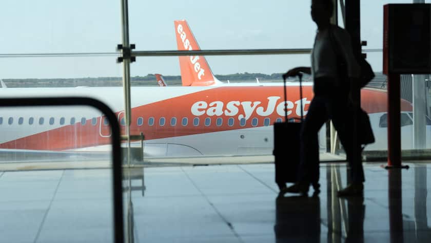 epa10116908 A man walks past an EasyJet plane at El Prat airport, Barcelona, Spain, 12 August 2022. The first day of the EasyJet pilots' strike in August has caused cancellations at El Prat and in Palma de Mallorca Airports. EPA/ALEJANDRO GARCIA