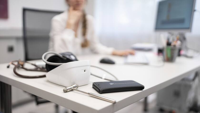 A general practitioner at the Seebach Medical Center in Zurich, Switzerland, listens to a patient, in the foreground on her desk are medical work utensils and a smartphone, photographed on 19 August 2019. (KEYSTONE/Gaetan Bally)Eine Hausaerztin im Aerztehaus Seebach in Zuerich hoert einem Patienten zu, im Vordergrund auf ihrem Schreibtisch liegen medizinische Arbeitsutensilien sowie ein Smartphone, aufgenommen am 19. August 2019. (KEYSTONE/Gaetan Bally)