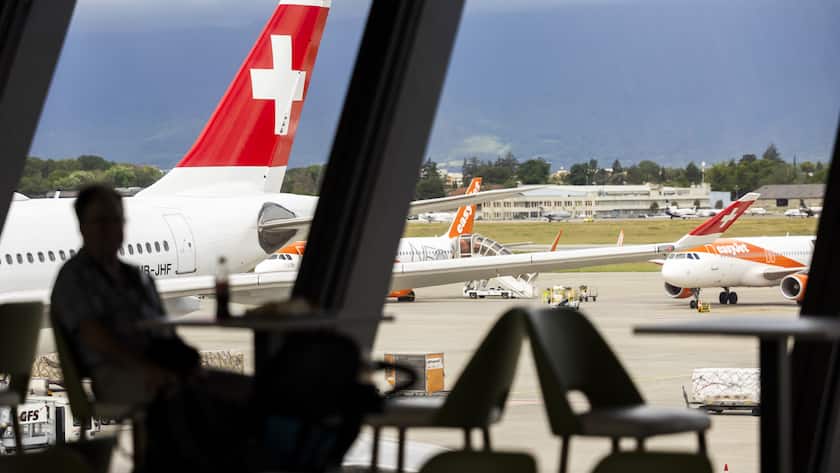 Un passager regardant un avion de la compagnie Swiss International Air Lines et des avions de la compagnie easyJet est photographie, lors d'une presentation de la strategie de developpement durable de Geneve Aeroport, ce mardi 11 juin 2024 a Geneve. (KEYSTONE/Salvatore Di Nolfi)