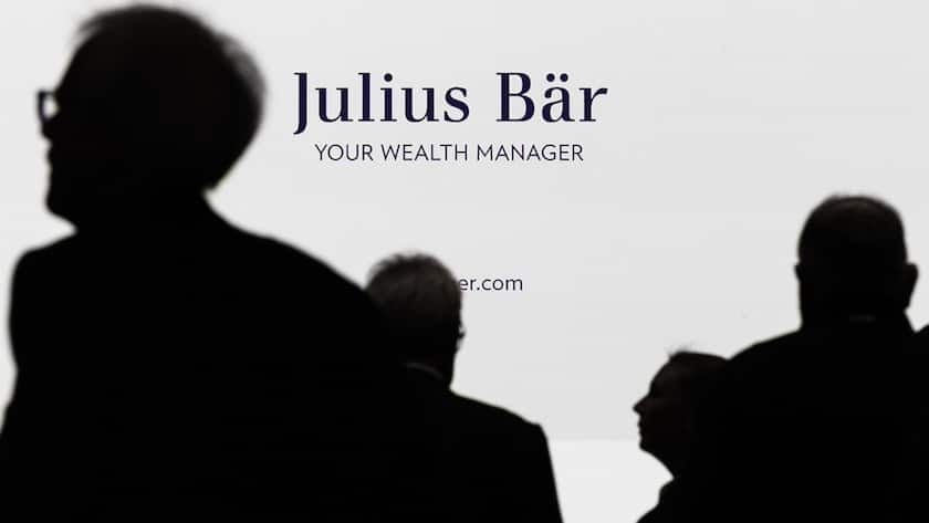 Shareholders are silhouetted against a screen showing the bank's logo during the Annual General Meeting AGM of the Julius Baer Group on Thursday, April 11, 2024 in Zurich, Switzerland. (KEYSTONE/Michael Buholzer)