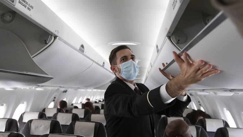 A cabin crew member of Swiss International Air Lines wearing a face mask to protect against the spread of coronavirus COVID-19 prepares the aircraft prior to departure to London during the resumption partially flights of Swiss International Air Lines following the lockdown to due lockdown measures against spread of coronavirus COVID-19, at the Geneve Aeroport, in Geneva, Switzerland, Monday, June 15, 2020. (KEYSTONE/Salvatore Di Nolfi)