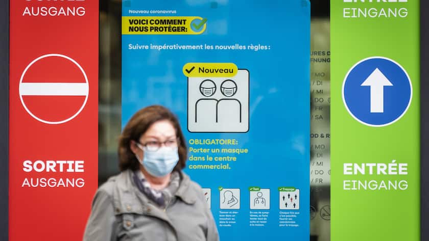Une personne portant un masque de protection marche devant une affiche de l'OFSP devant une Centre commercial le vedredi 16 octobre 2020 a Fribourg. Face a l'augmentation des nouveaux cas, les cantons sont en train de reevaluer leurs mesures sanitaires. Une rencontre avec le Conseiller federal Alain Berset est prevue aujourd'hui pour discuter de nouvelles mesures pour lutter contre le Coronavirus (Covid-19). (KEYSTONE/Jean-Christophe Bott)