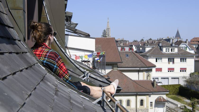 A woman enjoys the sun on the rooftop during the state of emergency of the coronavirus disease (COVID-19) outbreak, in Bern, Switzerland, Saturday, April 4, 2020. (KEYSTONE/Anthony Anex)
