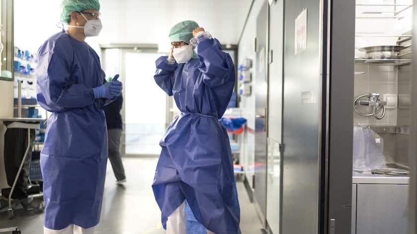 Eine Aerztin zieht sich eine neue Schutzmaske an im Gang der Covid-19-Intensivabteilung und spricht mit eine Kollege im Stadtspital Triemli am 10. Dezember 2020 in Zuerich. (KEYSTONE/Gaetan Bally)