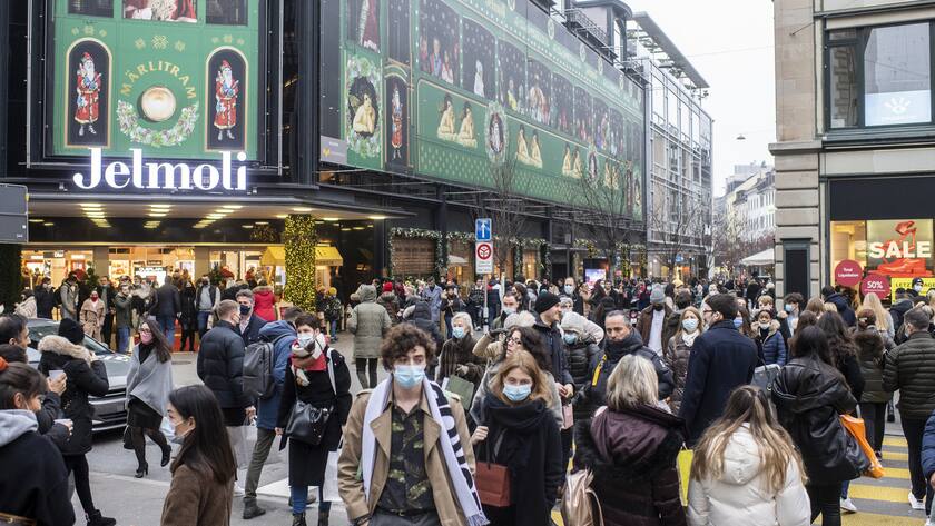 Menschen mit Atemschutzmasken laufen vor dem Warenhaus Jelmoli um einzukaufen, aufgenommen am Samstag, 19. Dezember 2020 in Zuerich. (KEYSTONE/Ennio Leanza)