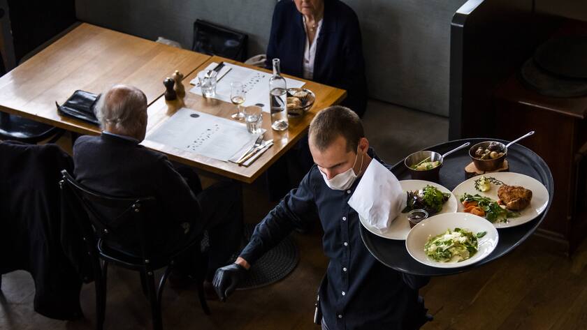 A waiter of "La Brasserie de Montbenon" restaurant brings dishes food to customers during the spread of the pandemic Coronavirus (COVID-19) disease in Lausanne, Switzerland, Monday, May 11, 2020. In Switzerland from today, the Swiss authorities lifted second part of the lockdown. (KEYSTONE/Jean-Christophe Bott)