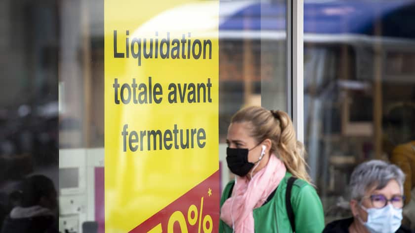 Une personne portant un masque de protection facial marche devant un magasin en liquidation totale avant fermeture lors de pandemie de Coronavirus (COVID-19) ce mardi 20 octobre 2010 a Lausanne. (KEYSTONE/Laurent Gillieron)