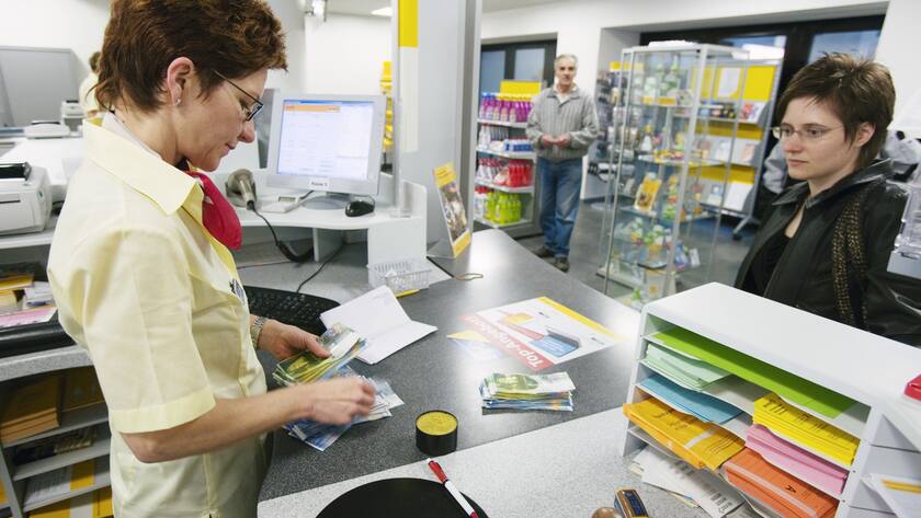 Irene Lerch, Angestellte der Post, zaehlt am Postschalter in Sursee am 2. Maerz 2007 das Geld, das eine Kundin eingezahlt hat. (KEYSTONE/Martin Ruetschi)