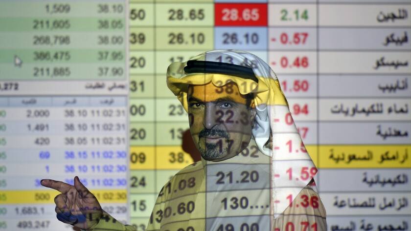 FILE- In this Dec. 12, 2019, file photo, a trader talks to others in front of a screen displaying Saudi stock market values at the Arab National Bank in Riyadh, Saudi Arabia. Saudi Aramco said Tuesday, May 4, 2021, it's profits soared by 30% for the first-quarter of the year, compared to last year, riding on the back of higher crude oil prices as some of the world's biggest economies claw their way out of recession and ease restrictions amid vaccine roll-outs against COVID-19.(AP Photo/Amr Nabil, File)