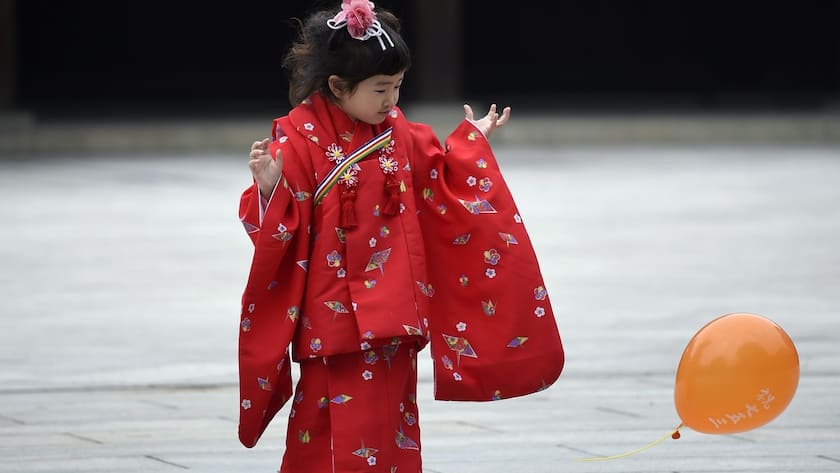 Ein junges japanisches Mädchen in einem Kimono spielt mit einem Luftballon.