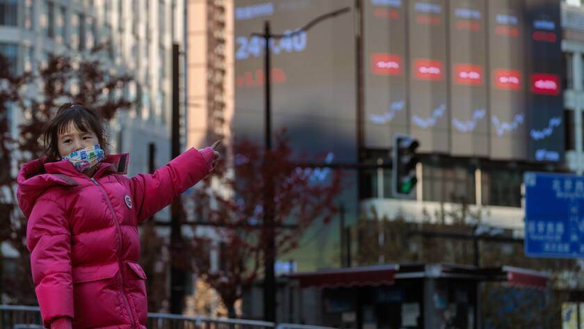 Ein Kind läuft auf der Strasse vor einem grossen Bildschirm, auf dem die neuesten Börsendaten angezeigt werden, in Shanghai, China.