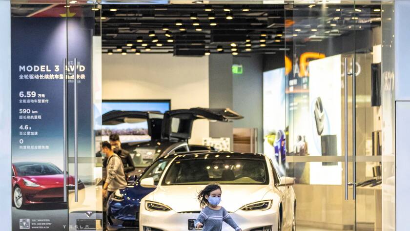 epa08272246 A girl wearing a mask runs in front of the Tesla store in Shenzhen, Guangdong province, China, 05 March 2020. The outbreak of coronavirus and COVID-19 has claimed ​in excess of 3,200 lives globally. EPA/ALEX PLAVEVSKI