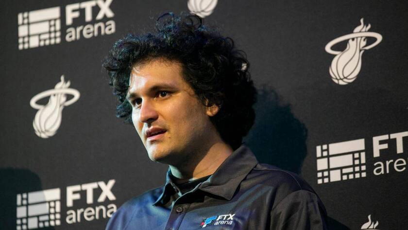 FTX-CEO Sam Bankman-Fried an einer Pressekonferenz vor einer schwarzen Wand mit FTX-Aufschrift.