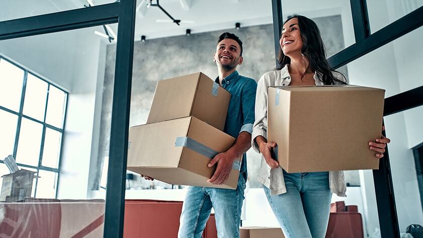A young married couple in the living room in the house unpack boxes with things. Happy husband and wife are having fun, are looking forward to a new home. Moving, buying a house, apartment concept.