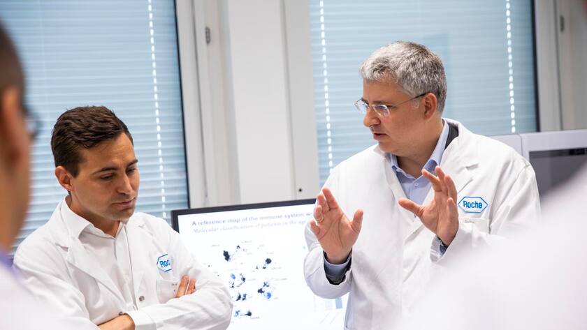 Roche-CEO Severin Schwan unterhält sich mit einem Mitarbeiter der Forschung.
